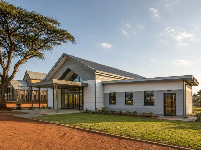 Metal building church — steel campus chapel with office expansion wing alongside existing main building, Kenya
