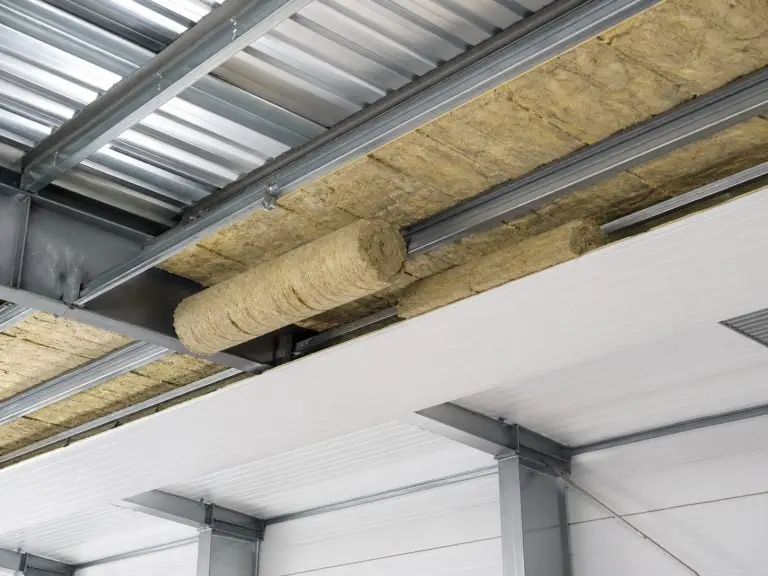 Metal building insulation installation — rock wool blanket between outer panel and inner liner for insulated metal building
