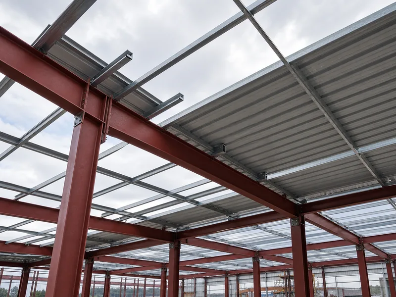 Ribbed metal roof panels installed over steel purlins on a steel-framed building under construction 