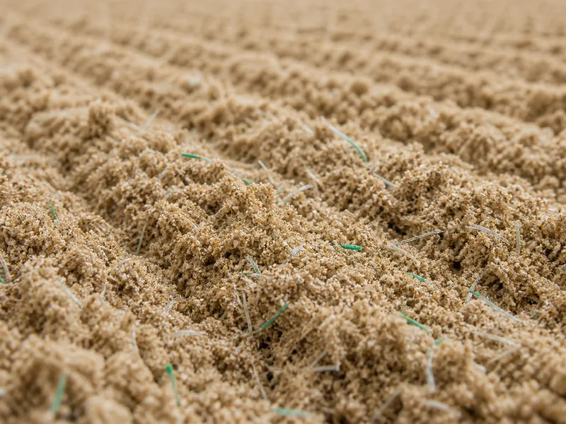 Close-up of a sand-and-fiber riding arena footing surface
