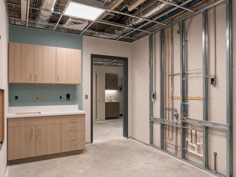 Exam-room interior with exposed HVAC ductwork and plumbing rough-in