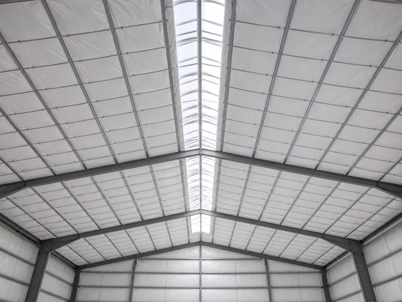 Banded fiberglass insulation held across steel roof purlins in a metal building