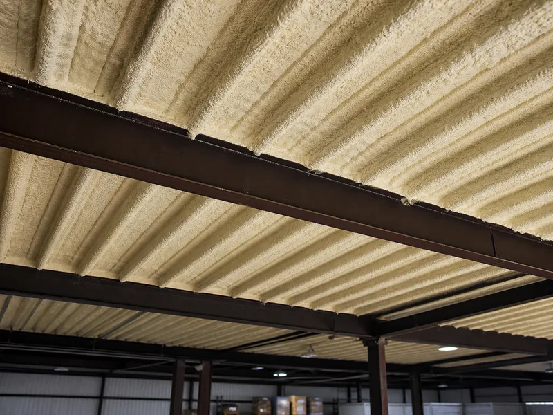 Closed-cell spray foam applied under an existing warehouse roof deck and purlins